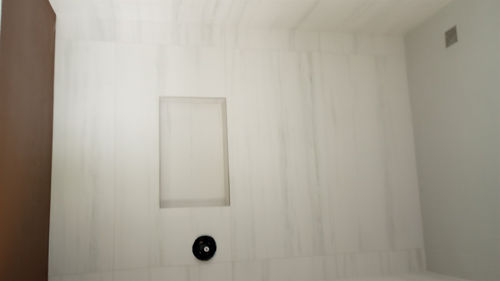 Marble-look shower niche with white marble veining, recessed shelf, and integrated valve plate