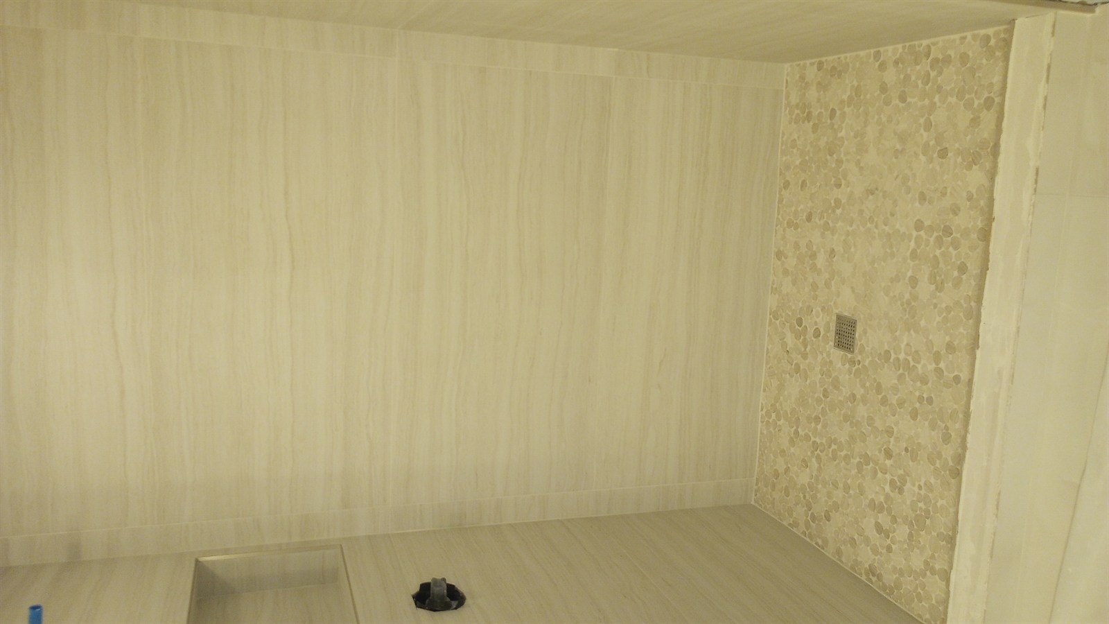 Master bathroom transformation Sarasota — finished shower with cream porcelain wood-grain tile and pebble mosaic accent wall